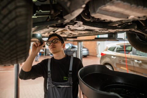 KFZ-Mechatroniker des Autohauses Hotz Automobile Garelegen leuchtet bei einem Auto in die Innenseite des Rades mit einer Taschenlampe.